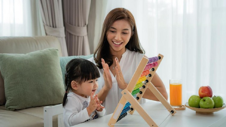 Happy Asian young mother and daughter playing with abacus, early education at home.