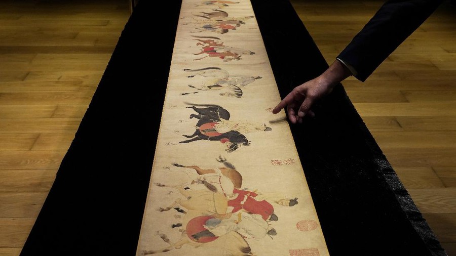 A Sotheby's employee presents the Chinese scroll, "Five Drunken Princes Returning on Horseback" from the period of Chinese Yuan Dynasty, by Ren Renfa during a media preview for the Sotheby's in Hong Kong on Wednesday, Sept. 23, 2020. The 700-year-old painted scroll has been sold for $41.8 million at an auction in Hong Kong. (AP Photo/Vincent Yu, File)