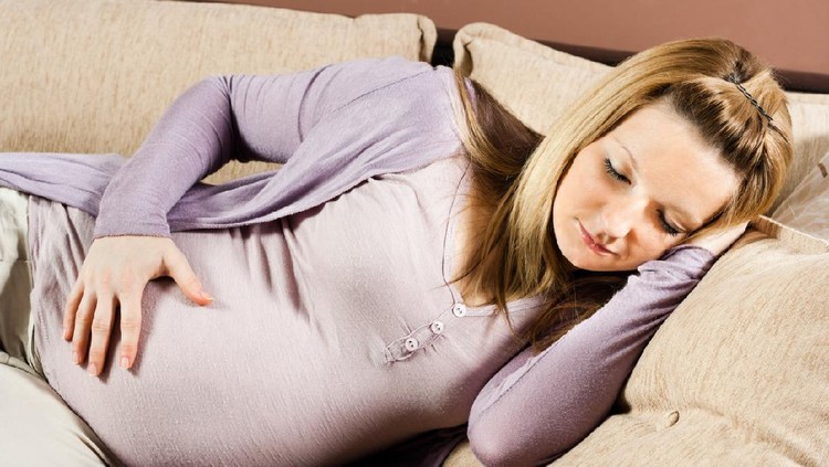 Pregnant woman is sleeping on sofa.