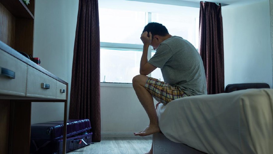 Man sitting on bed with head in hands