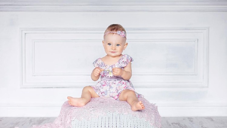 bayi perempuan Little pretty girl with blue eyes sits on a padded stool