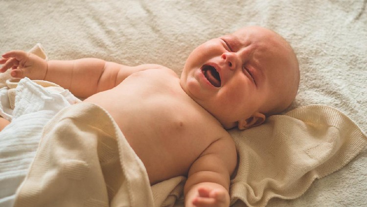 Crying hungry newborn baby lying on the bed. Love baby. Newborn baby and mother.