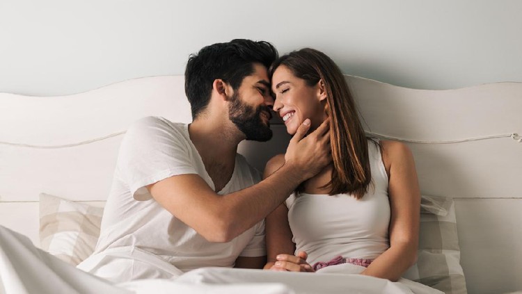 Affectionate young couple relaxing in bed and having a romantic moment