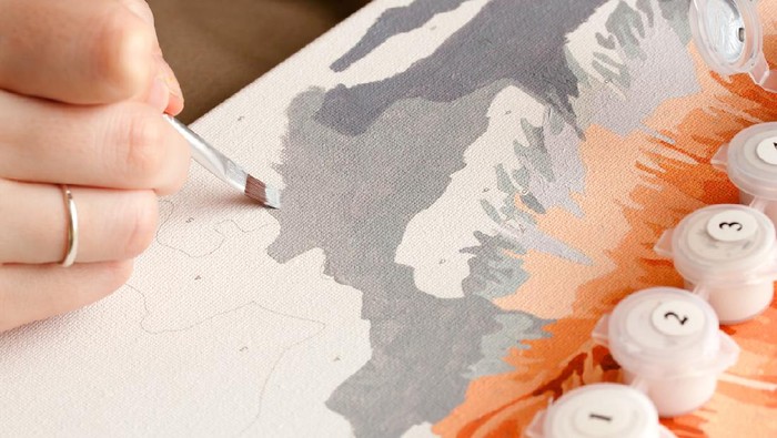 Female hand coloring paint by numbers picture. Creative hobby. Leisure activity at home during self-isolation COVID-19