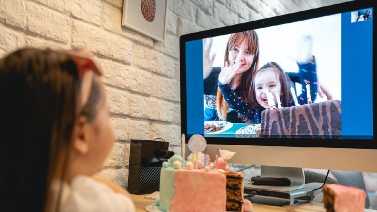 Ilustrasi video call Lovely preschool age girl celebrating her 5th birthday in home isolation because of pandemic of COVID-19 in her country while talking with abroad family on a computer.