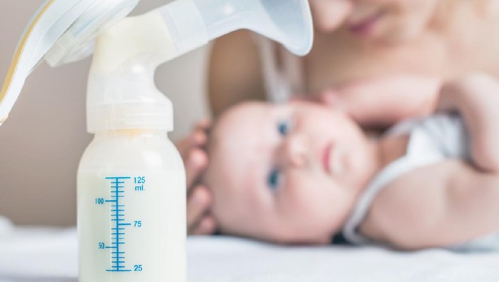 Manual breast pump, mothers breast milk is the most healthy food for newborn baby. Happy mother with baby at background