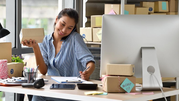 Working women at their store. They wearing casual clothing, accepting new orders online and packing merchandise for customer