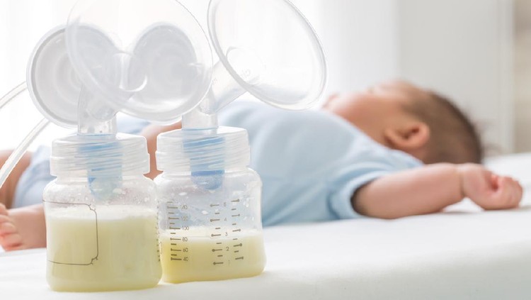 Breast milk pump and baby lying on the white bed