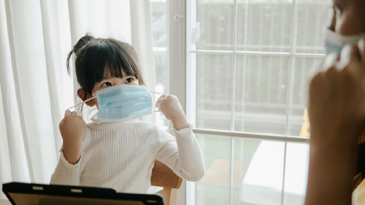 Asian businesswoman wearing protective face mask while working with laptop to protect pollution from dust PM2.5 and coronavirus covid-19