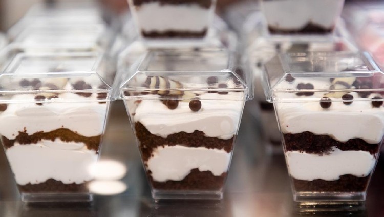 Chocolate and whipped cream dessert servings in closed plastic containers