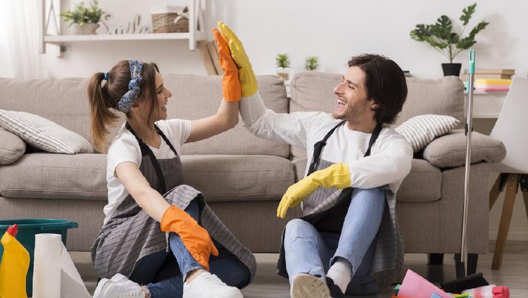 Young Asian woman tidying up the living room and wiping the coffee table surface with a cloth