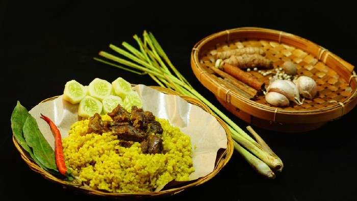 Yellow rice with mutton with some garnishes added like slices of cucumber, salam leaves (bay leaves/Syzygium polyanthum)  and big red chilli. Spices used in the dish contents placed on separated bamboo plate on the right side. Kebuli rice is served normally on special occasions.