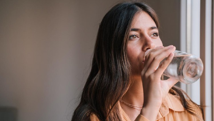 young beautiful woman by the window at home drinking water. Lifestyle