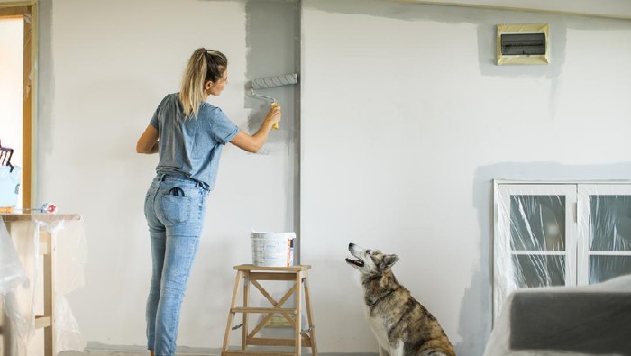 Portrait of a happy couple laughing while taking a break from painting - home improvement concepts
