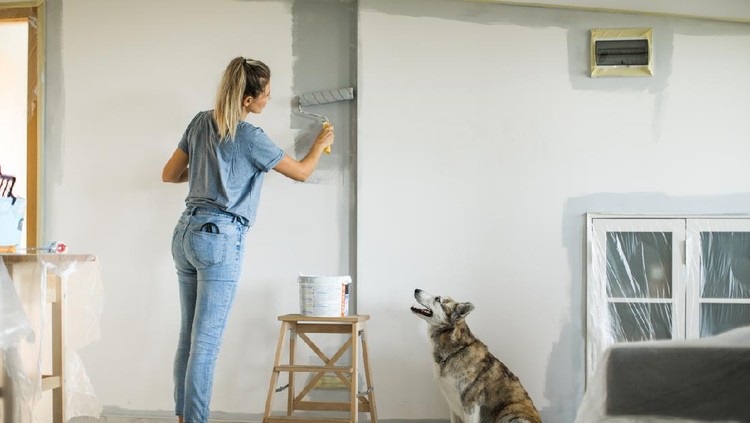 Portrait of a happy couple laughing while taking a break from painting - home improvement concepts