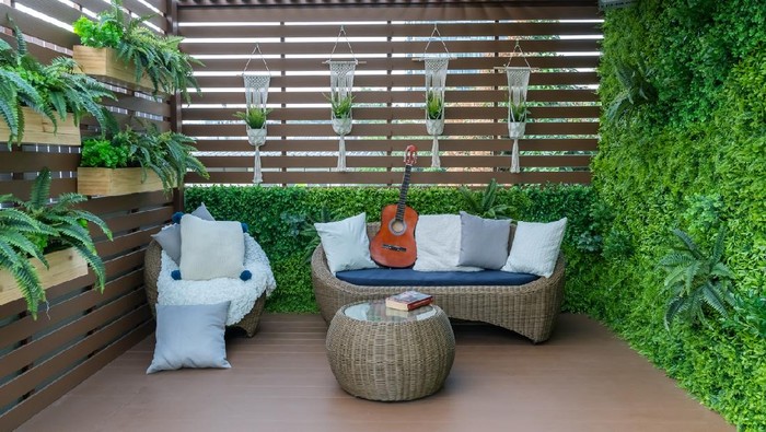Pretty woman grows tropical plants in her garden. Gardener in working outfit looking after different exotic flower and herb.