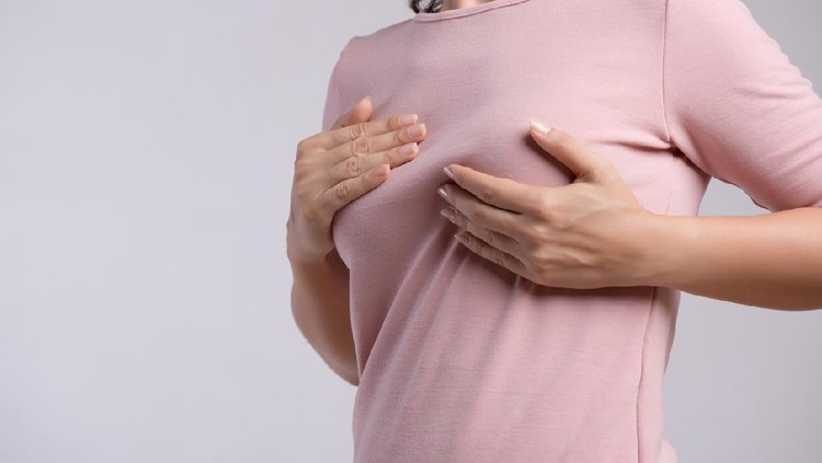 Ilustrasi periksa payudara Woman hand checking lumps on her breast for signs of breast cancer on gray background. Healthcare concept.