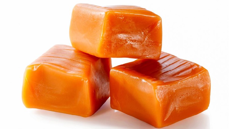 three toffee caramel candies close-up isolated on white background