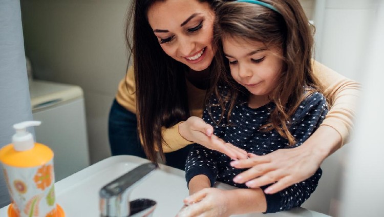 Happy woman washing hands with her daughter