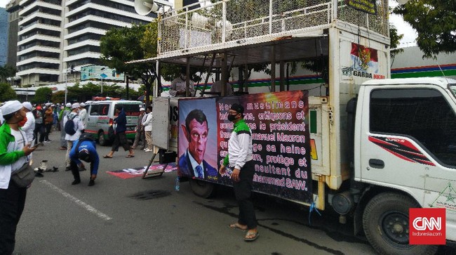 Massa aksi 211 membawa spanduk bergambar karikatur Presiden Prancis Emmanuel Macron yang berwajah iblis di mobil komnado.
