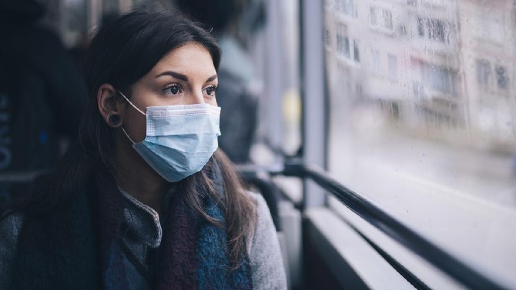 Young woman wearing protective face mask, she sitting in bus transportation in the city.