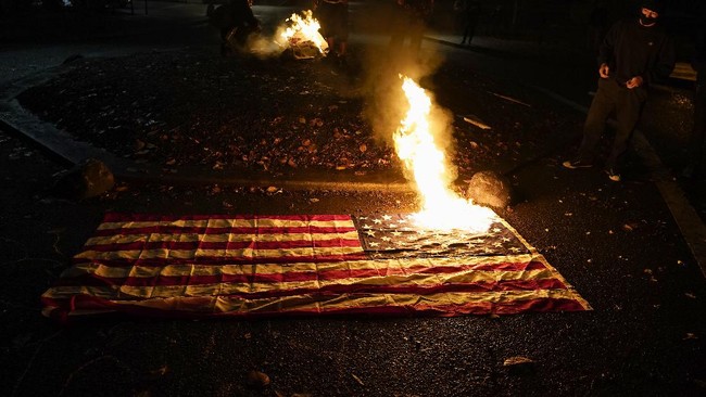 Aksi bakar bendera mewarnai demonstrasi di tengah penghitungan suara pemilu AS di Portland, Oregon.