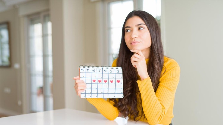Young woman holding menstruation calendar serious face thinking about question, very confused idea