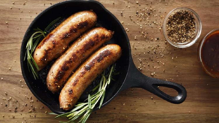 Ilustrasi sosis panggang Three sausages in a cast iron skillet with seasoning