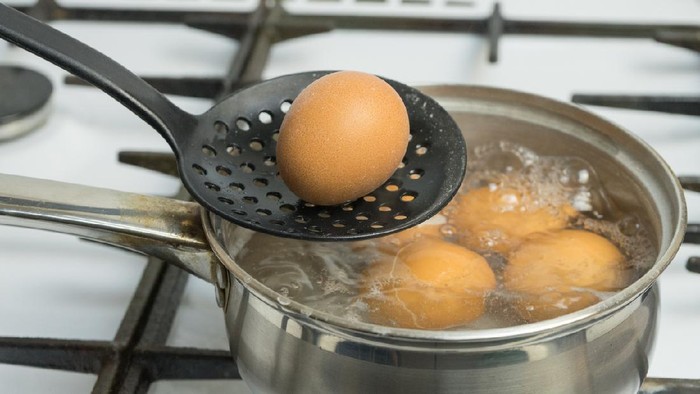 Chicken eggs boil in water. Pan with the product on a gas stove.