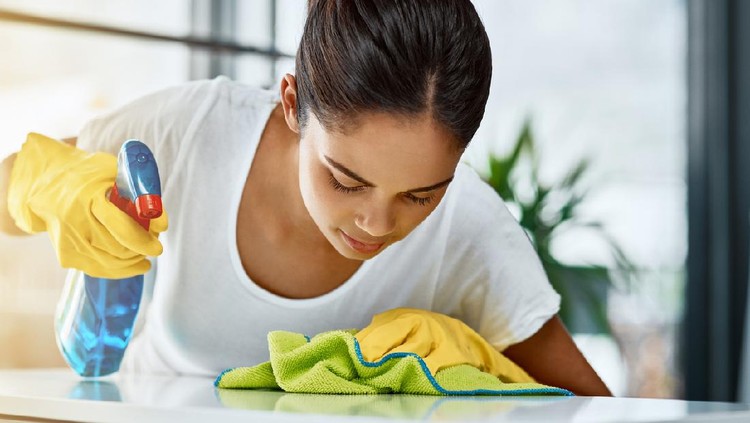 Shot of a young attractive woman cleaning a table at home