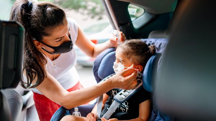Portrait of a mother fastening her daughter safely in a car seat
