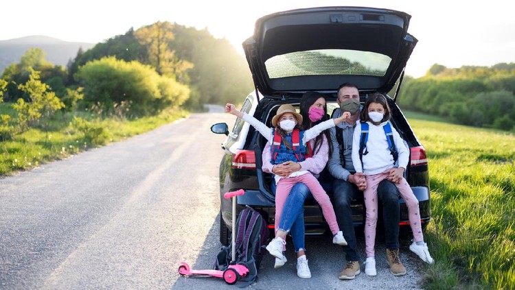 Liburan saat Corona Front view of family with two small daughters on trip outdoors in nature, wearing face masks.