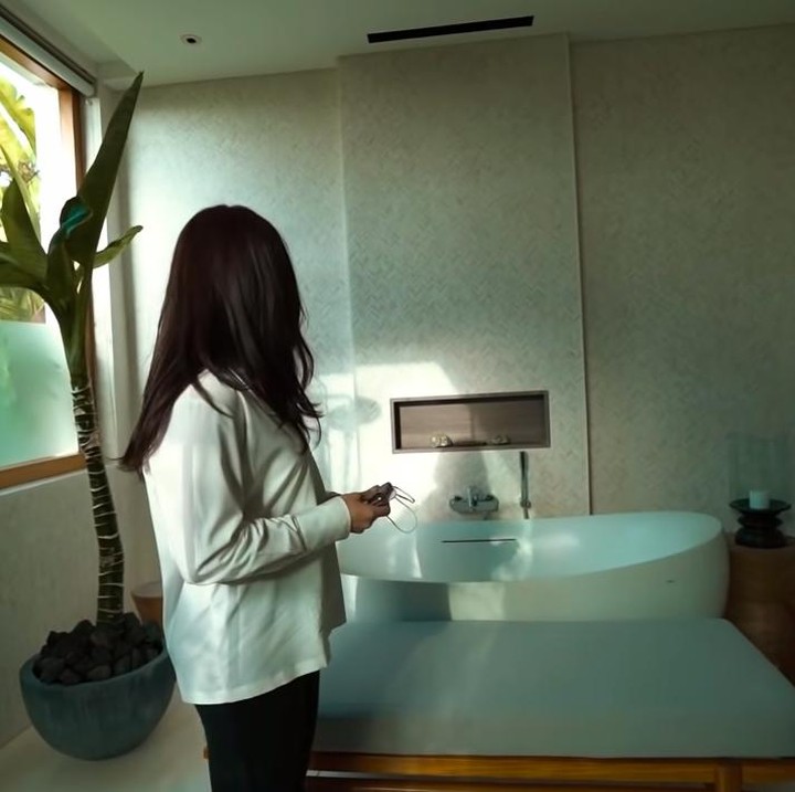 <p>Kamar mandi di vila ini terlihat minimalis didominasi warna putih. Ada tanaman hijau yang menambah suasana alami di sudut kamar mandi. (Foto: YouTube Nikita Willy Official)</p>