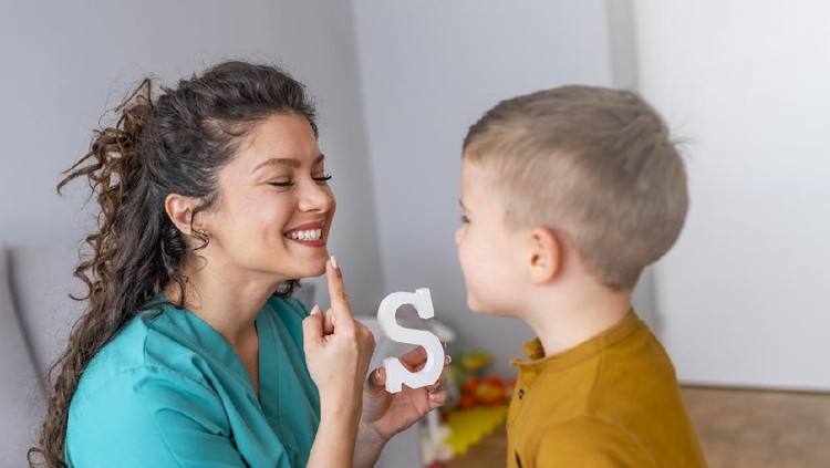 Cute little boy at speech therapist office. Shot of a speech therapist during a session with a little boy. Boy and young woman teacher during private home lesson