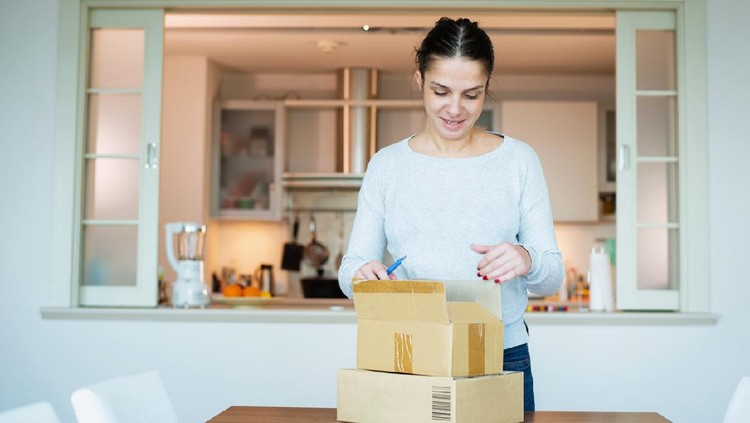 A woman opening boxes containing products she purchased online.