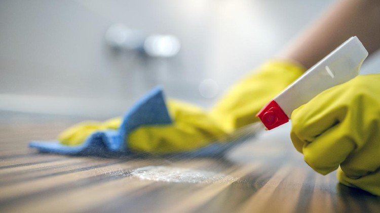 Photo of Woman or man cleaning kitchen cabinets with sponge and spray cleaner. Female or male hands Using Spray Cleaner On Wooden Surface. Maid wiping dust while cleaning her house wearing yellow protective gloves, close-up