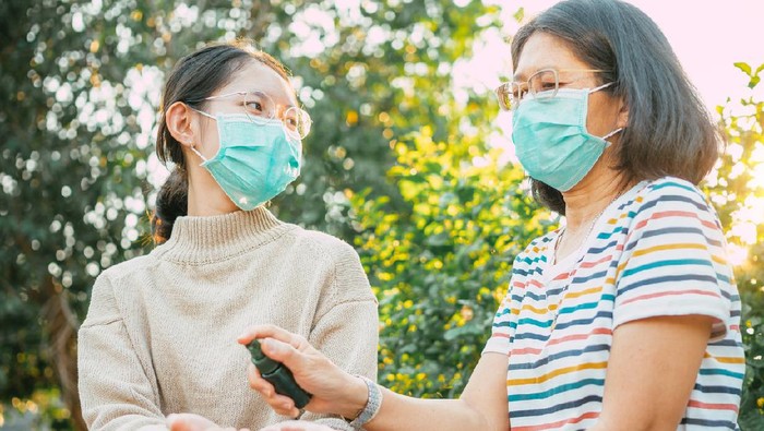 Asian people wearing protect mask and spray disinfectant alcohol on hand to prevent  spreading of the coronavirus ( Covid-19)