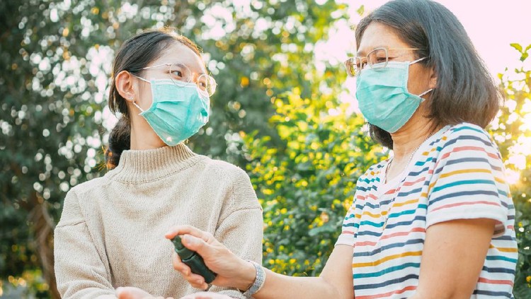 Asian people wearing protect mask and spray disinfectant alcohol on hand to prevent  spreading of the coronavirus ( Covid-19)