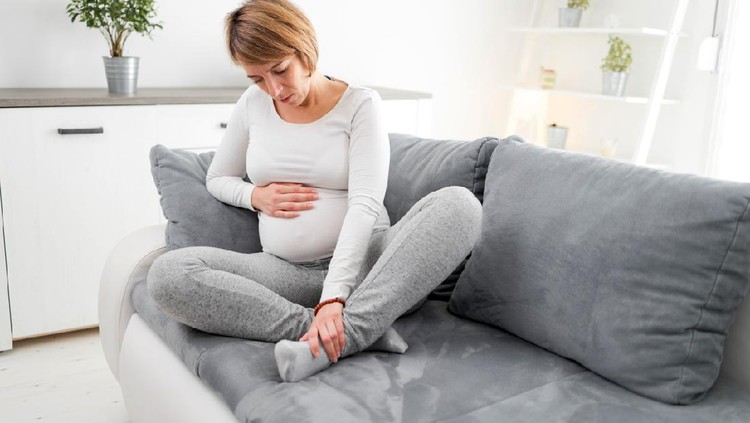 Pregnant tired exhausted woman with hand, leg and pain issues at home on a couch, being sick.