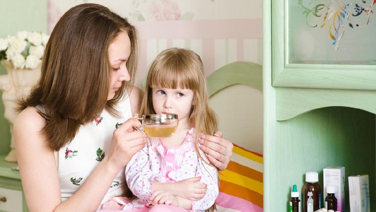 mother gives to drink to the sick child