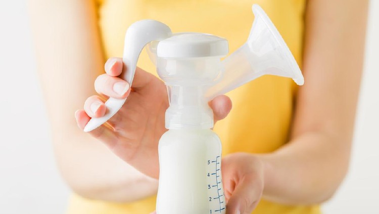 ASI Perah Young mother hands holding full plastic breast pump bottle. Closeup. Preparing milk for baby feeding. Front view.