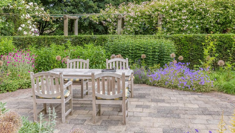 Wooden table and chairs in a beautiful ornamental garden