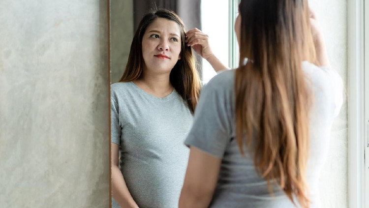 hamil Asian pregnant woman looking herself in the mirror, Asian pregnant woman's portrait.
