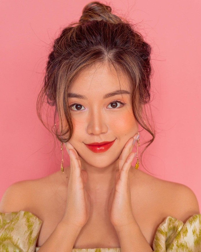 Bergaya sun-kissed look, Titan Tyra memadukan eyeshadow dan blush on bernuansa peach dengan lipstik peachy red. Ia lalu menata rambutnya dengan gaya messy bun yang semakin menambah kesan summer vibes. (Foto: instagram.com/titantyra)
