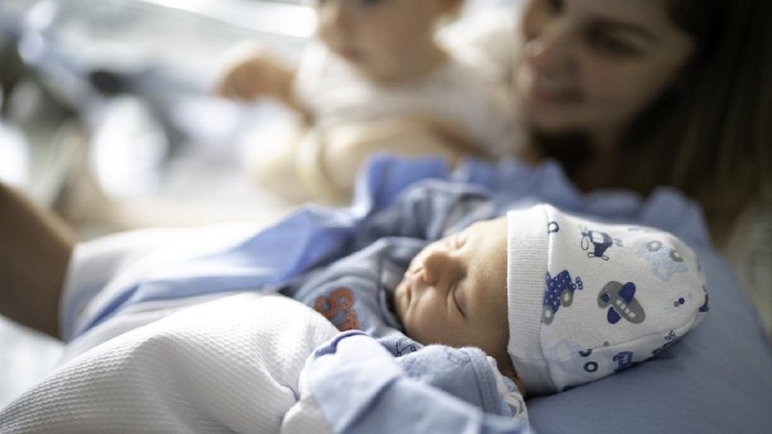 Mother and sleeping newborn and son at hospital