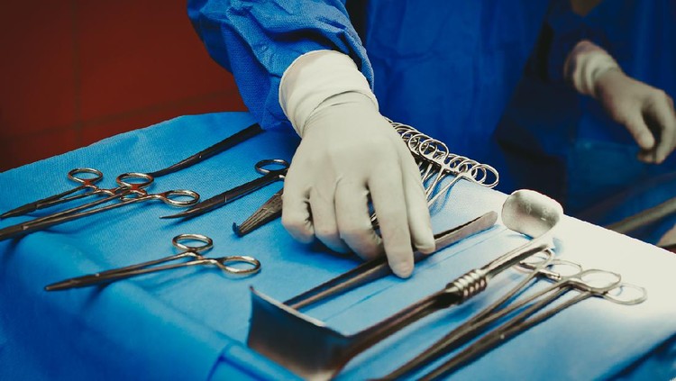 Close-up of surgeons hand holding surgical instruments in the operating room, Surgical tools lying on the table