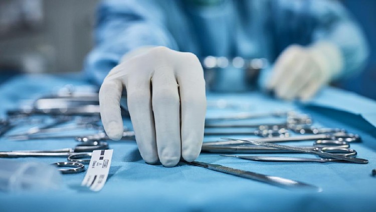 operasi Close-up of surgeons hand holding surgical instruments in the operating room, Surgical tools lying on the table