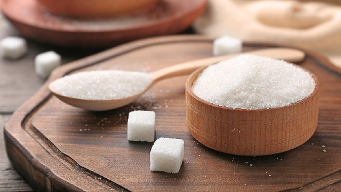 Bowl and spoon with pure sugar on wooden board