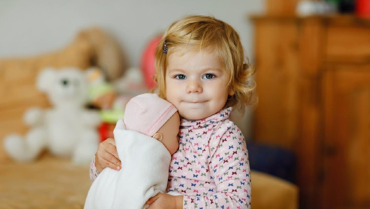 main boneka Adorable cute little toddler girl playing with doll. Happy healthy baby child having fun with role game, playing mother at home or nursery. Active daughter with toy