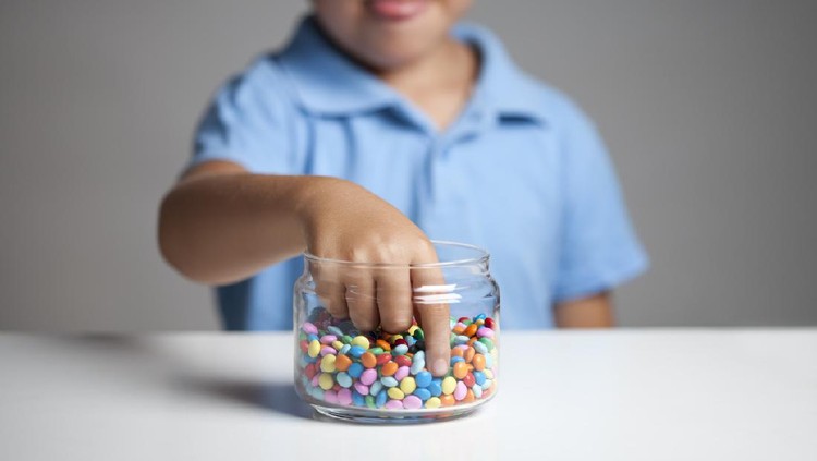 Anak makan Little boy licking his lips while taking candy from the candy jar.